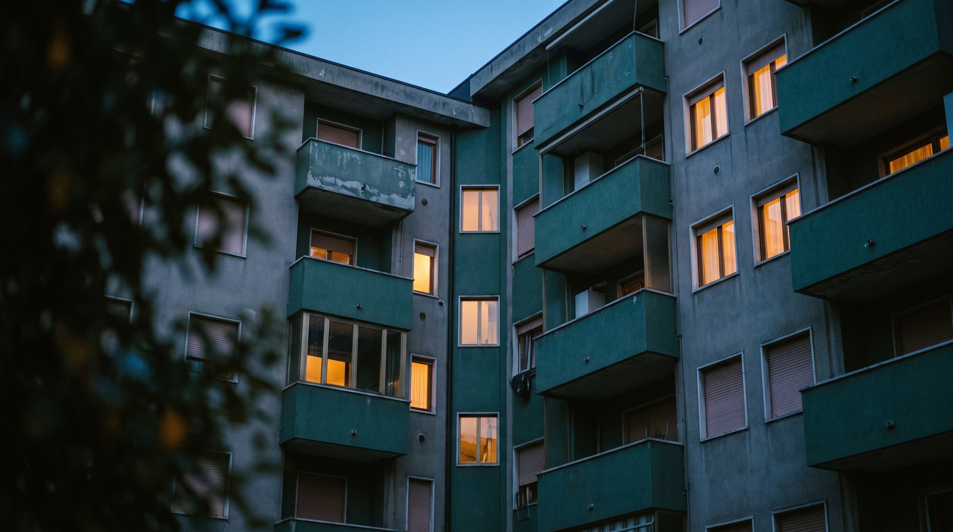 Facciata di un edificio residenziale al crepuscolo, con alcune finestre illuminate